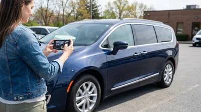Person using a smartphone to film a car rental walkaround in a Pennsylvania parking lot