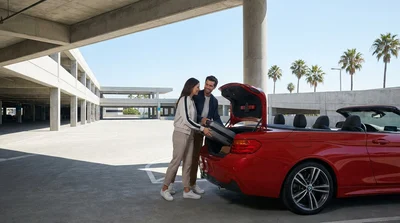 Shuttle bus picking up passengers with luggage outside a Los Angeles airport terminal for car hire