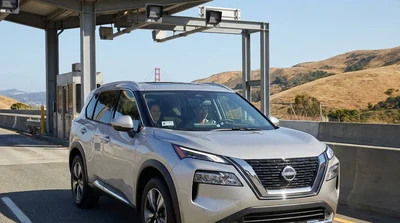 White car rental driving across the Golden Gate Bridge in San Francisco under a clear sky