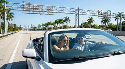 Silver car rental driving under a toll gantry on a sunny express lane in Miami