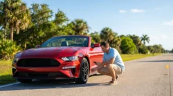Driver checking the engine of a broken down car hire on a sunny Florida highway