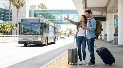 Passengers with luggage waiting at the car rental shuttle stop outside SFO Terminal 2 in San Francisco
