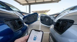 Driver holding a charging cable next to an electric car rental at a Texas charging station