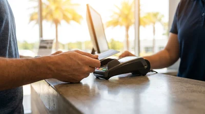 Close-up of hands passing a credit card to an agent at an Orlando car hire desk