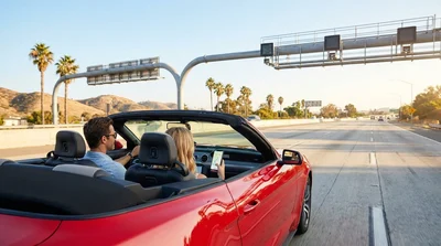 Smartphone mounted on the dashboard of a car rental driving on a sunny California highway toll road