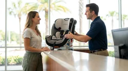 Rental agent handing a child car seat to a family at a car hire counter in Orlando