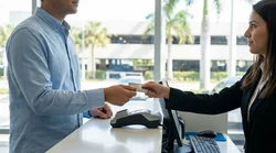 Person handing an embossed credit card to a clerk at a Florida car hire desk
