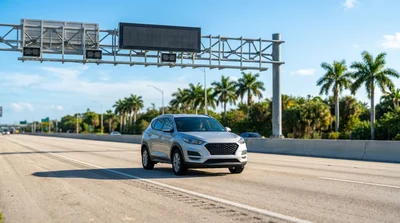 White car rental driving in an express lane on a sunny Florida highway with palm trees