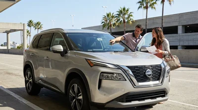Customer inspecting the windshield of a car rental at an outdoor pick-up lot in Los Angeles