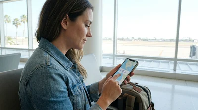 Smartphone displaying Apple Maps on the dashboard of a car rental parked near a sunny California beach