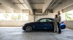 Person inspecting a scratched vehicle roof in a Florida car rental parking garage