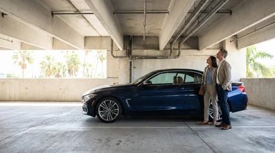 Person inspecting a scratched vehicle roof in a Florida car rental parking garage