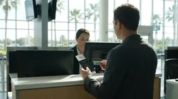 Customer handing a passport and credit card to an agent at an Orlando car hire desk