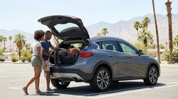 Multiple suitcases loaded into the open trunk of a compact SUV car rental parked on a sunny Las Vegas street