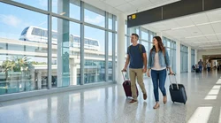Travelers with luggage walking through a Miami airport terminal toward the car rental center