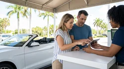 A white SUV car rental parked next to a sandy beach with tall palm trees in Florida