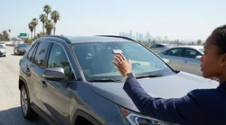 Modern car rental driving under an overhead Metro ExpressLanes sign on a sunny Los Angeles highway