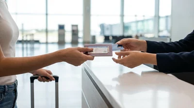 A person handing documents to an agent at a car rental desk inside Philadelphia Airport in Pennsylvania