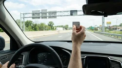 Silver car rental driving through an E-ZPass toll plaza on a New York highway