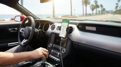 Smartphone in a dashboard holder displaying a navigation map inside a California car rental on a sunny highway