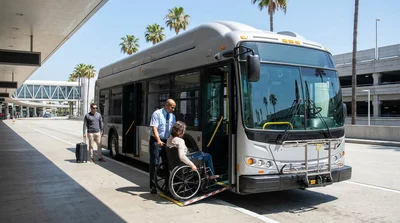 Accessible car hire shuttle bus with an extended ramp parked outside the LAX terminal in Los Angeles