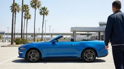 A couple driving their car rental along a sunny coastal highway in California with ocean views