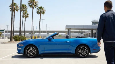 A couple driving their car rental along a sunny coastal highway in California with ocean views