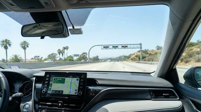 A car hire driving on a sunny Los Angeles freeway lined with iconic palm trees