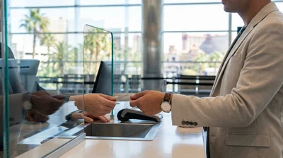 Person handing two credit cards to a clerk at a car rental desk in Las Vegas
