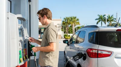 Person inserting a credit card into a gas pump while fueling a car rental in Florida