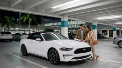 Customers standing at the brightly lit Hola car hire counter inside Miami Airport