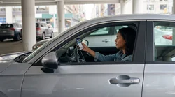 Driver using a smartphone inside a car rental parked on a New York street