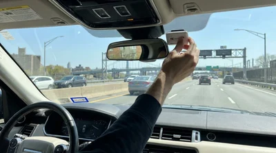 E-ZPass tag on the windshield of a car rental driving on a New York highway