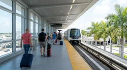 Travelers walking with luggage from the transit platform to the car hire center in Miami