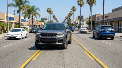 A car hire driving on a sunny, multi-lane Los Angeles street lined with palm trees