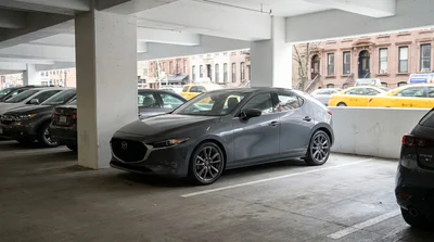 Compact car rental parallel parked between two vehicles on a street in New York