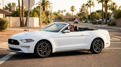 A white car rental stopped at a four-way stop sign on a sunny street in California