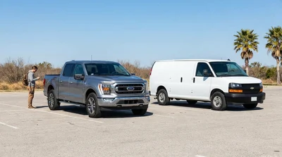 White pickup truck and passenger van parked on a sunny desert road during a Texas car hire trip