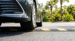 Close up of a car rental driving over a yellow speed bump on a sunny street in Florida