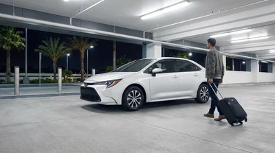 A traveler at a brightly lit car rental counter inside Miami airport at night