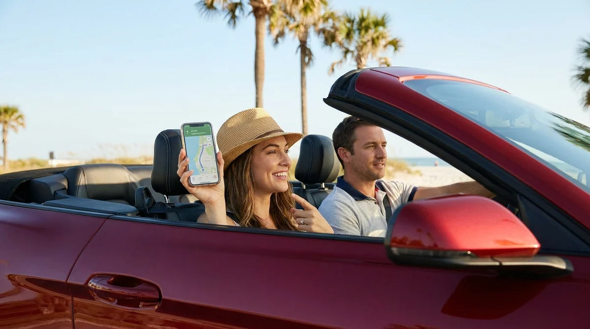 Smartphone displaying a map app mounted on the dashboard of a car rental driving on a sunny Florida highway