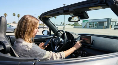 Hand touching a dashboard screen displaying Bluetooth settings inside a California car rental