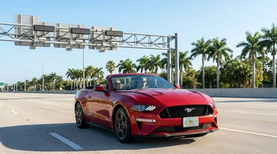 White car rental driving under a cashless toll gantry on a sunny Florida highway