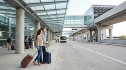White airport shuttle bus arriving at Newark Terminal A for car hire passenger pickup in New York