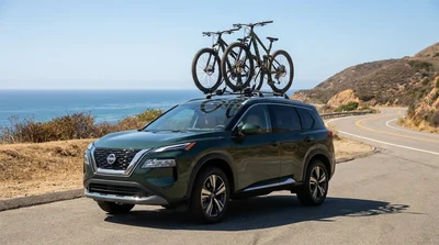 Car rental SUV with a roof rack holding bicycles parked along a scenic coastal road in California