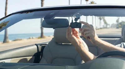 Dash cam mounted to the windshield of a car rental looking out over a sunny coastal highway in California
