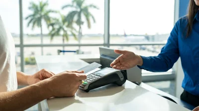 Customer handing a credit card to an agent at a car rental counter in Miami