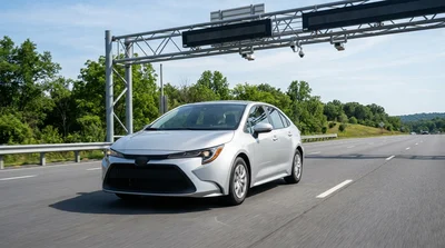 Modern car rental passing under an electronic toll gantry on a sunny Pennsylvania highway