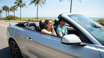 Modern car rental driving along a sunny highway lined with palm trees in Florida