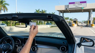 Silver car rental passing through an electronic toll booth on an Orlando highway